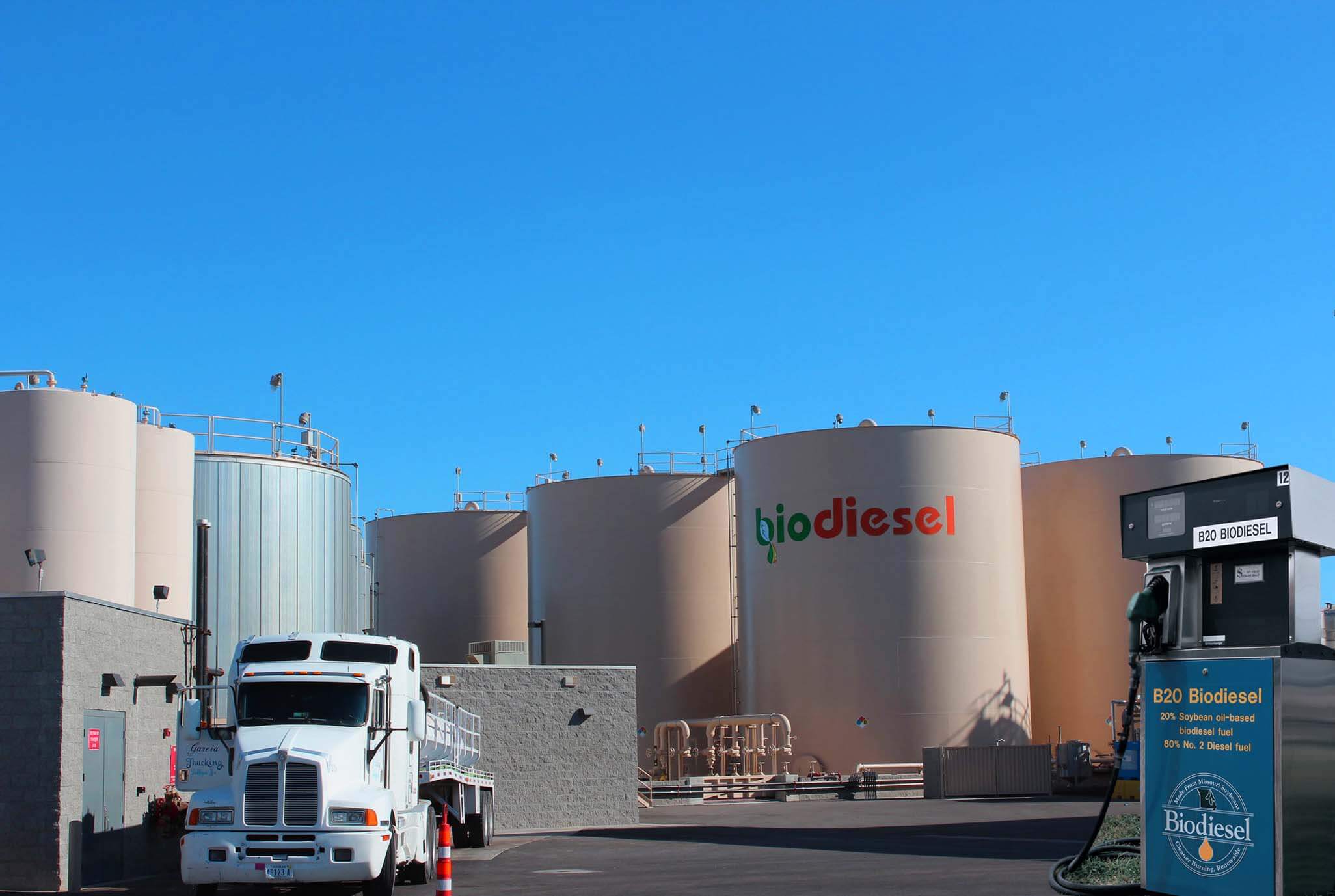 Foto mostrando tanques de armazenamento de biodiesel numa usina sob um céu azul de brigadeiro. No pátio aberto há uma carreta e uma bomba de biodiesel. A foto ilustra a notícia de que a venda de biodiesel superou a meta no novo modelo de comercialização