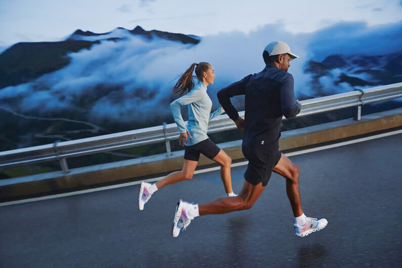 Imagem de uma mulher e um homem correndo numa estrada para ilustrar que um tênis de corrida tem espuma feita da captura de carbono.