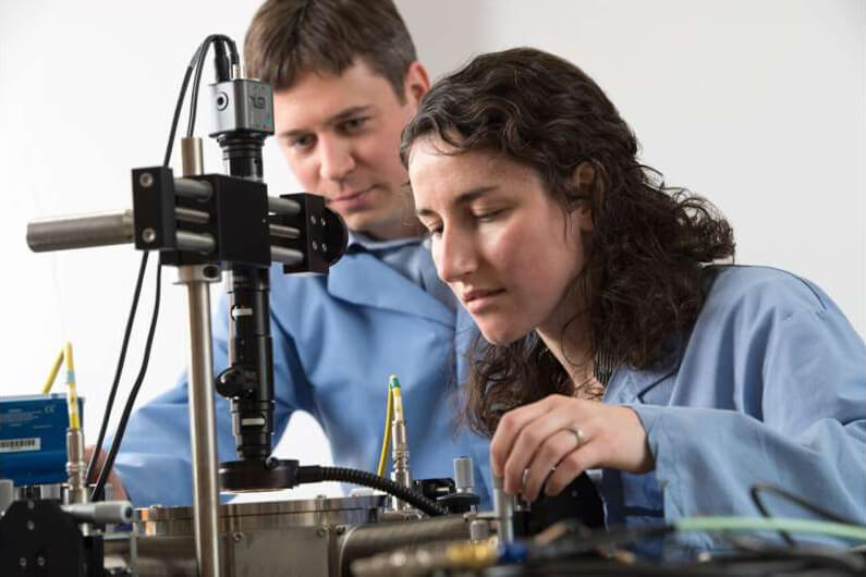 Foto de dois pesquisadores (um rapaz e uma moça) fazendo um experimento de laboratório para ilustrar que hidrogênio produzido da água e da luz é opção de biocombustível.