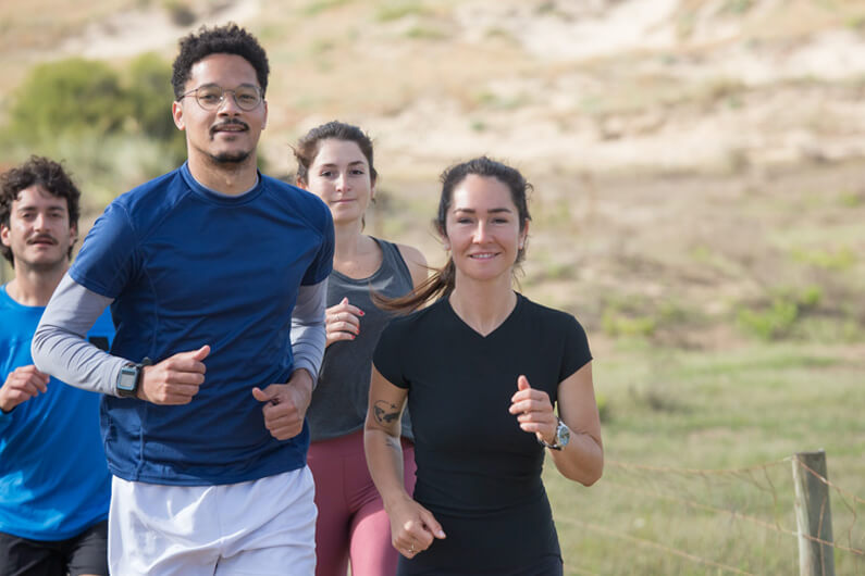 Foto de quatro pessoas (duas mulheres e dois homens) correndo, ilustra o post como correr pode te ajudar a lidar com o estresse no trabalho.