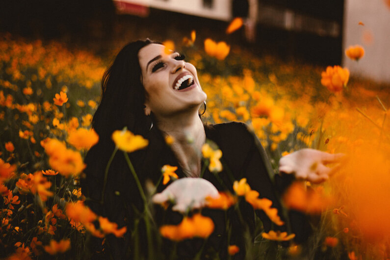 Imagem de uma mulher no meio de um campo florido para ilustrar post sobre como as plantas podem mudar nosso estado de espírito.