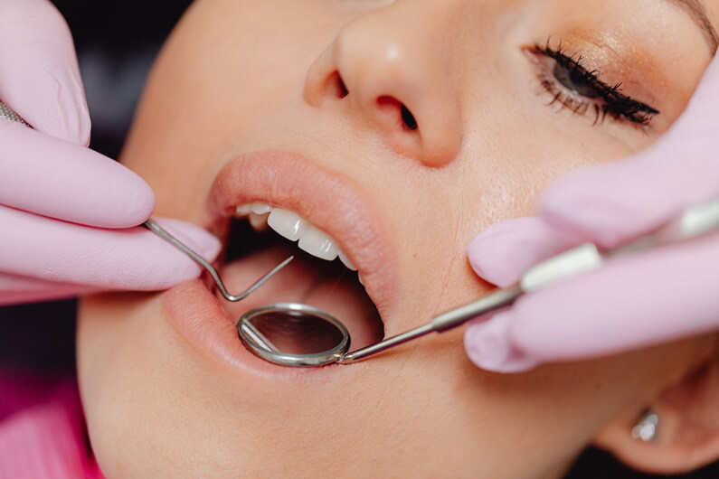 Imagem mostrando uma mulher com a boca aberta e aparelhos odontológicos para ilustrar que a regeneração de dentes humanos está cada vez mais próxima.