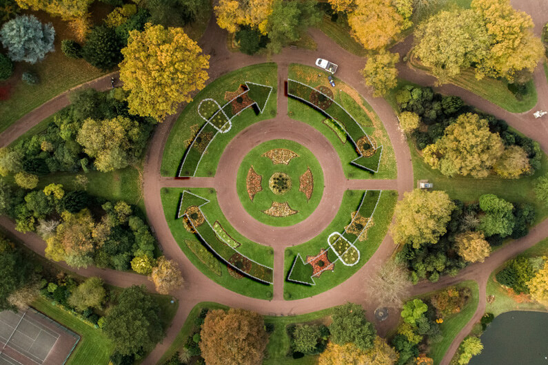 Imagem aérea de um parque com uma praça em seu centro rodeado de árvores e com quatro setas formando um círculo ilustram o post cujo título diz que economia circular com fórmula vencedora pode atrair empresas.