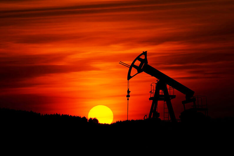 Imagem de um cavalo perfurador de petróleo sob um céu avermelhado e um pôr do sol ao fundo para ilustrar post cujo título diz que a UE visa cortar 85% do consumo de combustíveis fósseis até 2040.