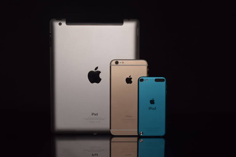 Imagem de um iPad, um iPod um iPhone sobre um fundo escuro ilustra post cujo título diz que uma nova lei nos EUA vai afetar os fabricantes de celular.